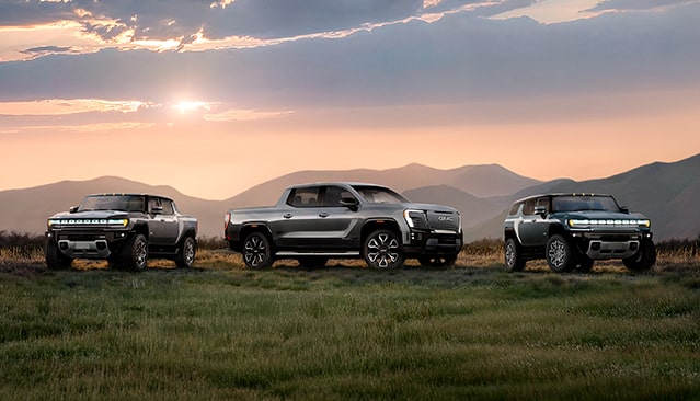 The GMC EV Line-up Parked in Front of a Mountain Range at Sunset