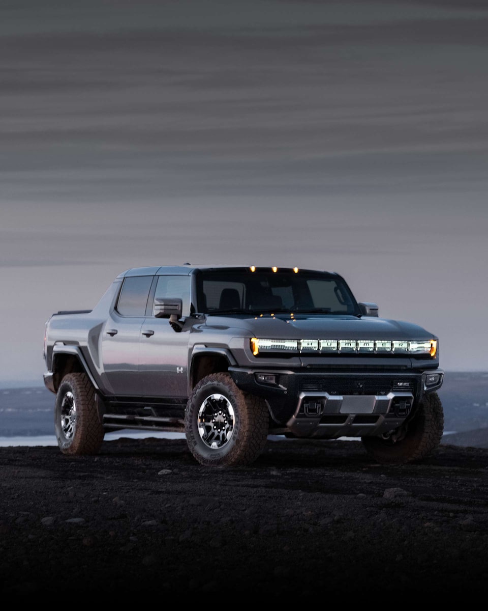 Front Three-Quarters View of the 2025 GMC HUMMER EV Pickup Truck Parked on Muddy Terrain