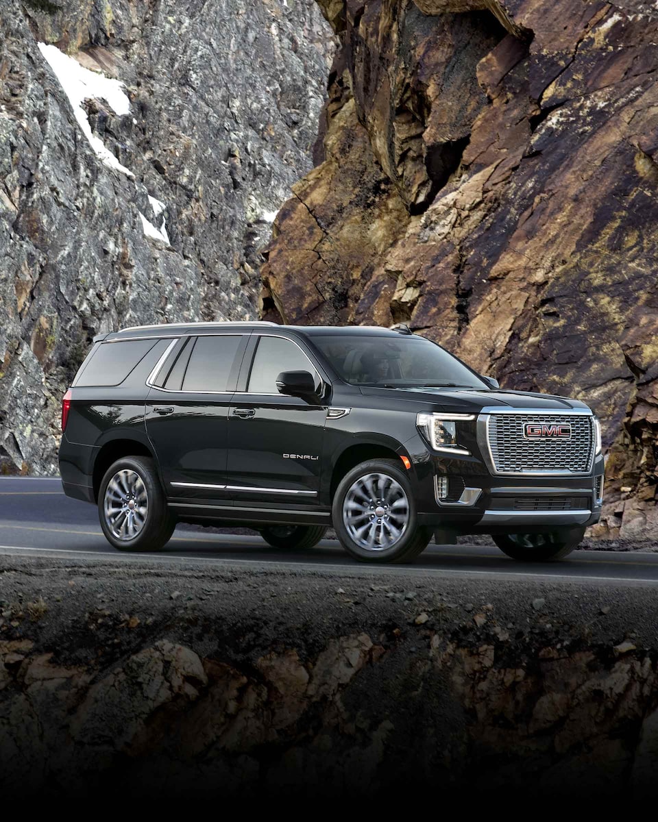 Wide Side View of a 2024 GMC Yukon Large SUV Parked with Mountains in the Background