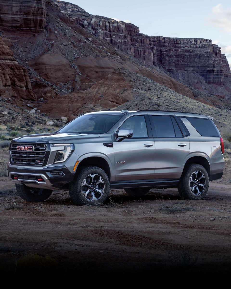 Wide Side View of a 2024 GMC Yukon Large SUV Parked with Mountains in the Background