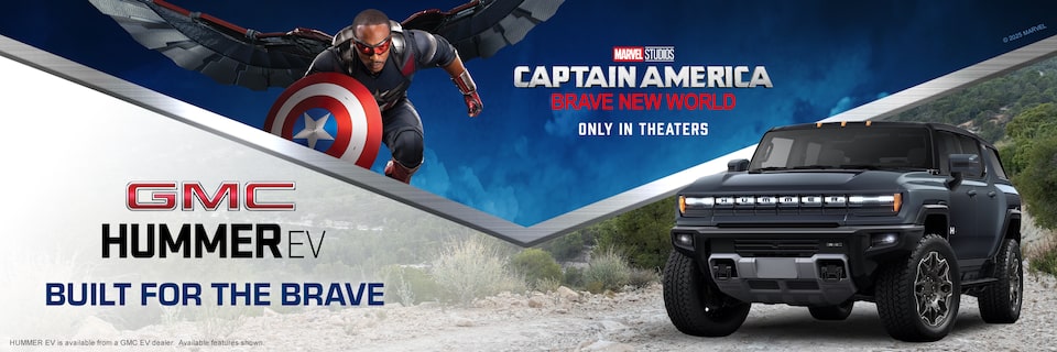 Marvel Studios Captain America From the Movie "Brave New World" with a HUMMER SUV to the Right, Parked on a Gravel Road with a Text Overlay of "GMC HUMMER EV Built For The Brave".