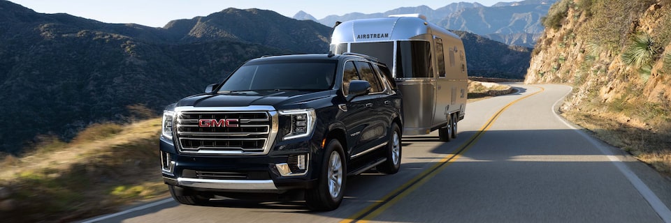 Three-Quarters View of a Black GMC SUV Pulling a Trailer Through the Mountains