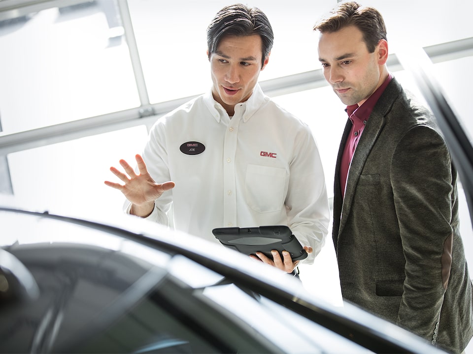 Image of two men discussing a vehicle at a GMC Business Elite Dealer. 