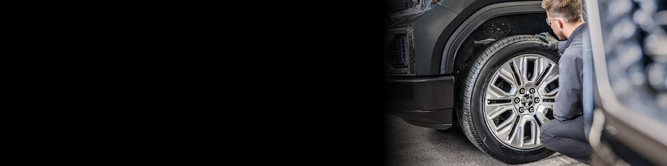 GMC Certified Service Technician Inspecting a Wheel on a Vehicle