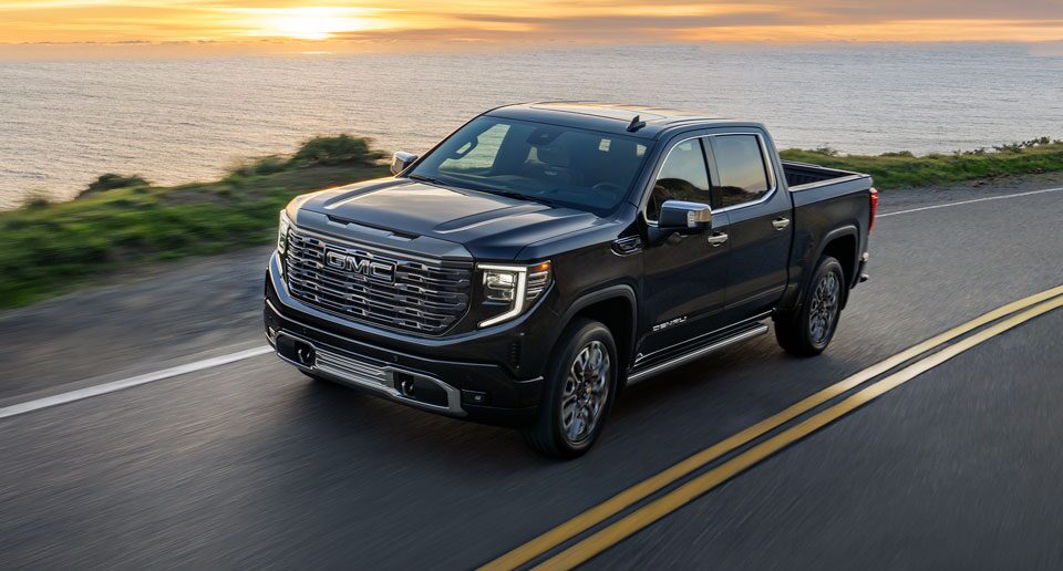 GMC Truck Driving on a Road Next to a Lake