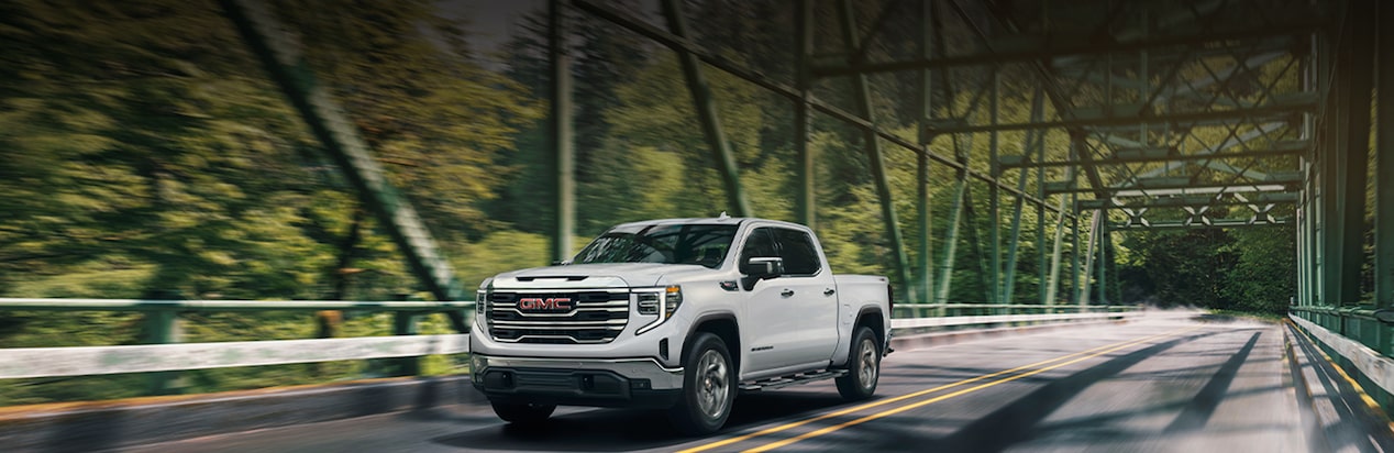 A White GMC Truck Driving Over a Bridge