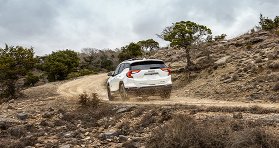 A White GMC SUV Driving Up a Mountain Trail