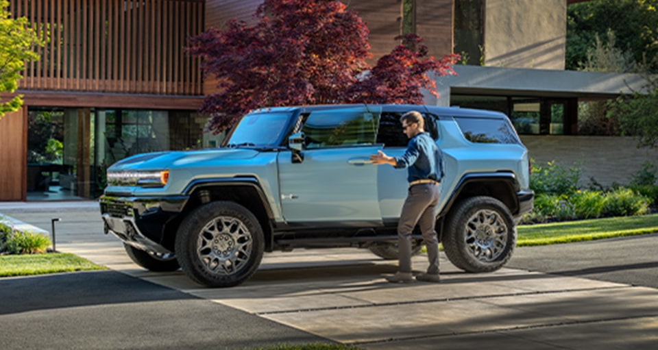 A Blue GMC HUMMER EV SUV With a Man Entering Driver Side