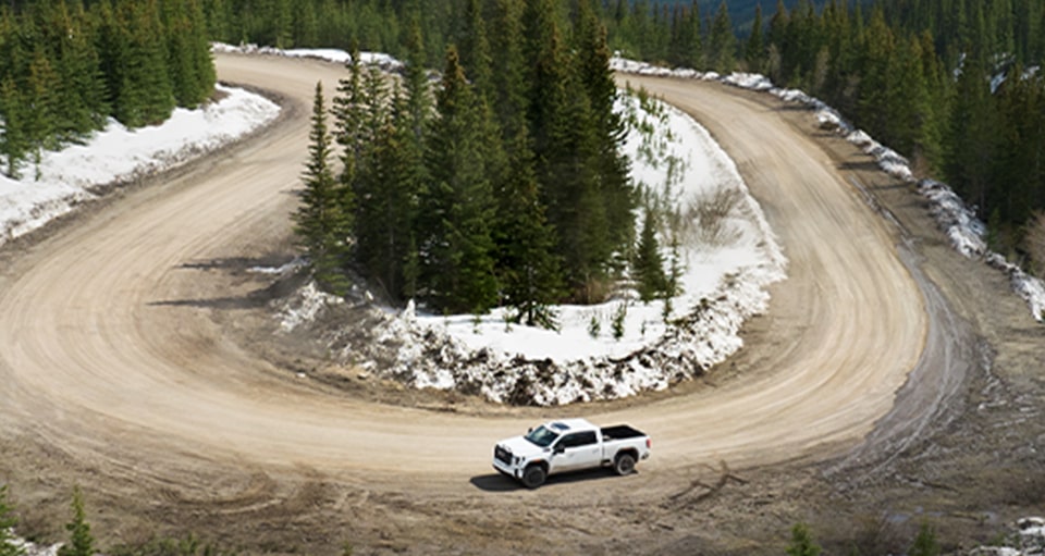 A White GMC Truck Rounds a Curved Mountain Trail