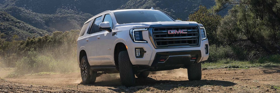 A GMC Yukon AT4 SUV Driving on a Dirt Path With Trees in the Background