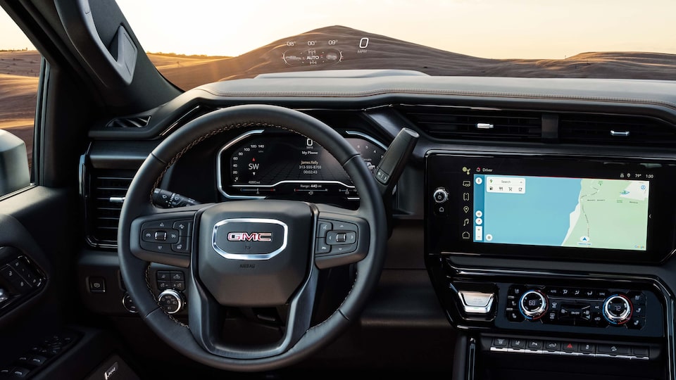 Close-up of the GMC Sierra AT4 Interior With View of the Steering Wheel and Infotainment Screen With Navigation App in Use