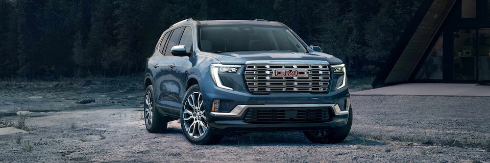 Front Three-Quarters View of a GMC Acadia Denali SUV Parked on a Sandy Path