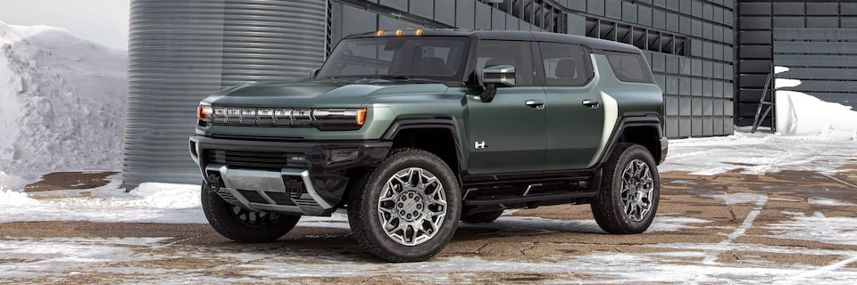 Front Three-Quarters View of a HUMMER EV SUV Parked on a Snowy Road In Front of a Business