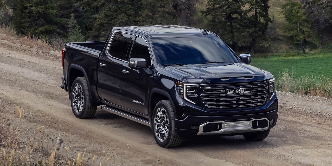 A GMC Sierra Truck Driving Down a Dirt Road with a Beautiful Scenic Mountain Valley View in the Distance