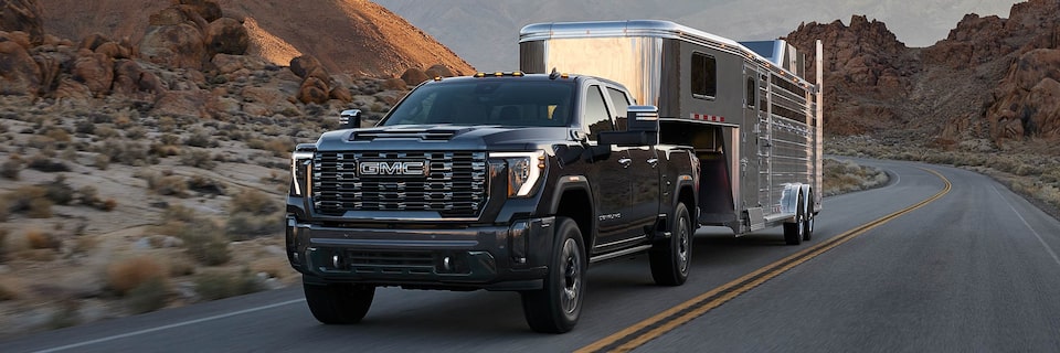 A GMC Truck Hauling a Trailer Driving on an Open Road Through the Mountains