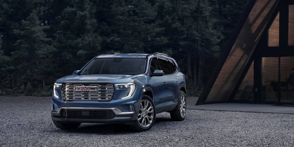 Wide Front Three-Quarters View of a 2024 GMC Acadia Parked Next to a Cabin at Night