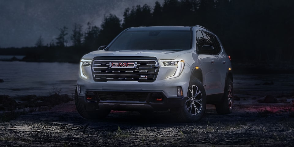 Front Three-Quarters View of a 2024 GMC Acadia AT4 Surrounded by Trees at Night