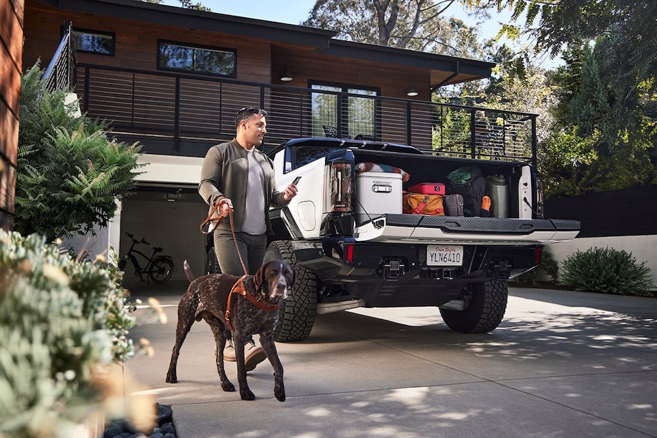 A Man Walking His Dog In Front of a Home While Using His Smartphone