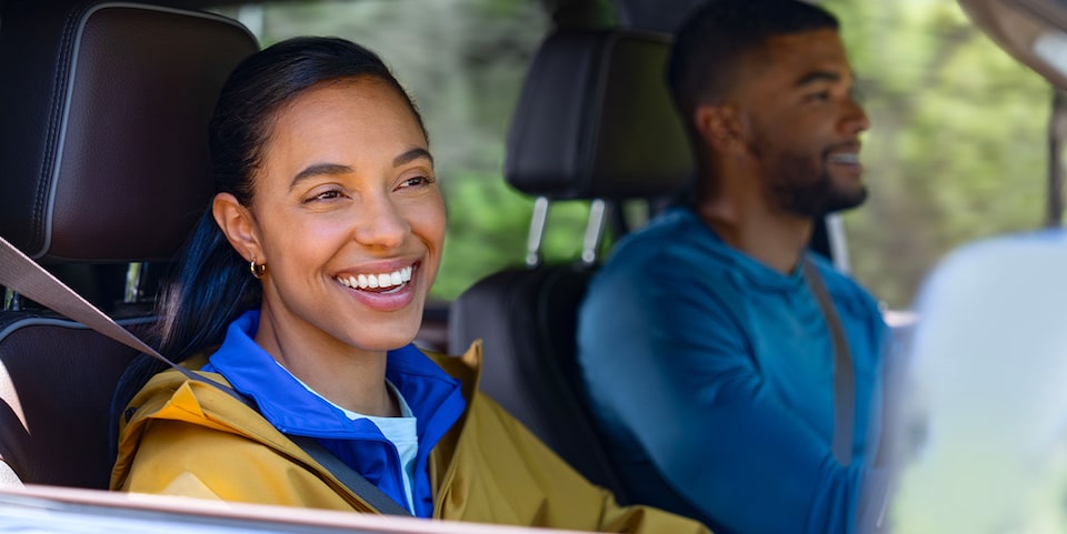 Two Smiling People Sitting Inside of a Vehicle