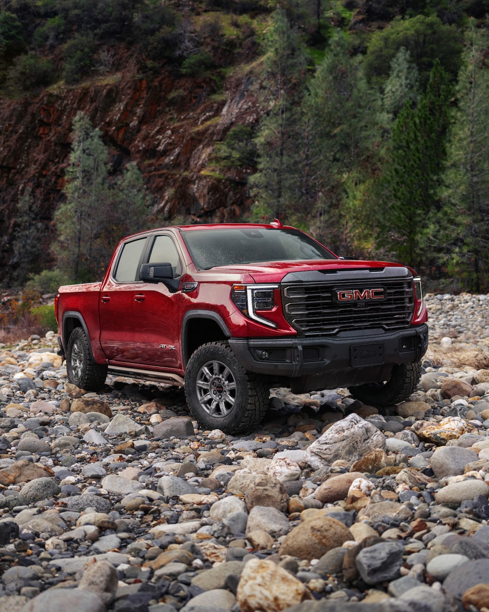 A GMC Truck Driving on a Rocky Path Surrounded by Trees