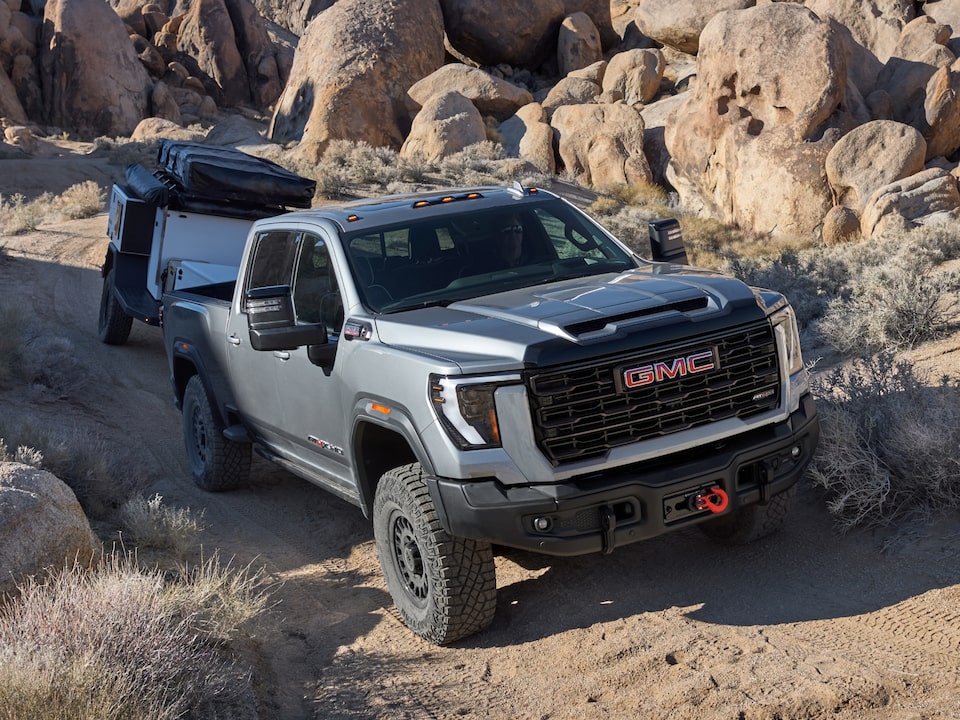 A GMC Truck Hauling a Small Camper Though a Rocky Mountain Path