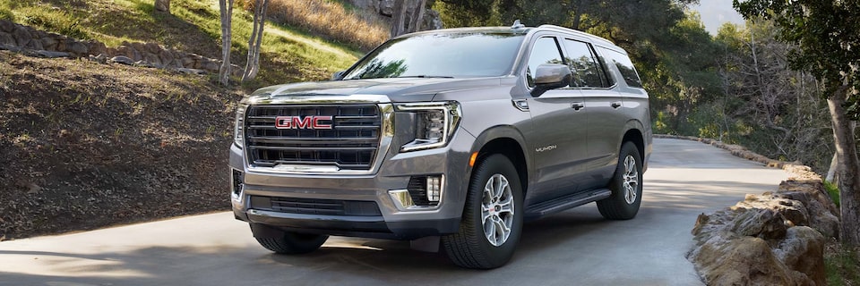 2024 GMC Yukon Three-Quarter View Driving Down Wooded Road