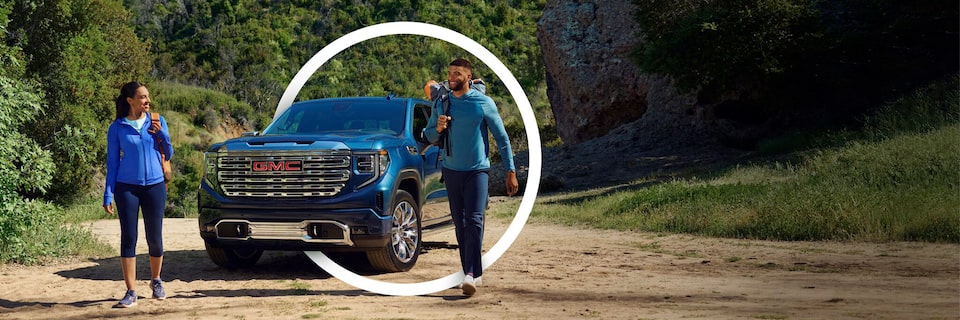 Two People Walking In Front of a GMC Vehicle with a Circle Graphic