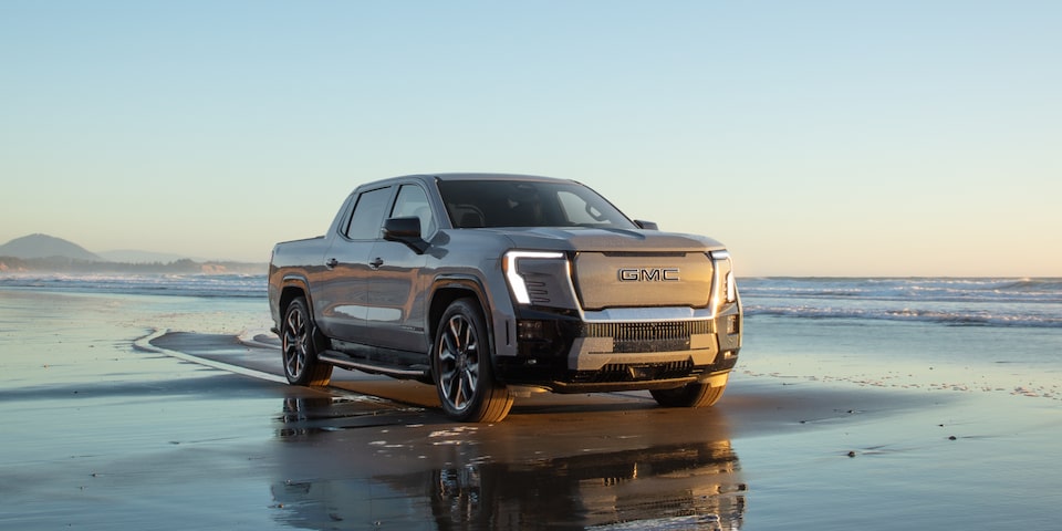 Front Three-Quarter View of the GMC Sierra EV Truck on a Beautiful Beach at Sunrise