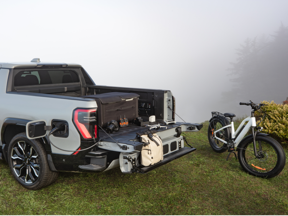 A GMC Sierra EV Truck Parked Next to a Foggy Cliff with an Electric Bike Nearby